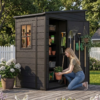 Woman organizing flower pots inside an open 5x4 dark gray resin garden storage shed on a backyard patio.